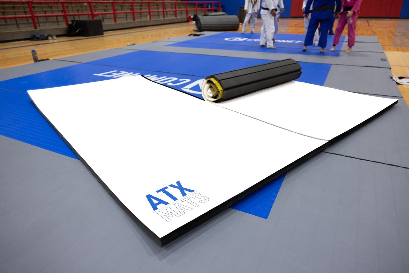 White ATX roll-out mat being unrolled at a BJJ tournament